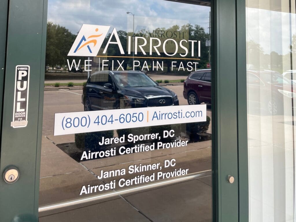 Close up view of the glass front door at Airrosti Fairfield Village. Airrosti details printed directly on door.